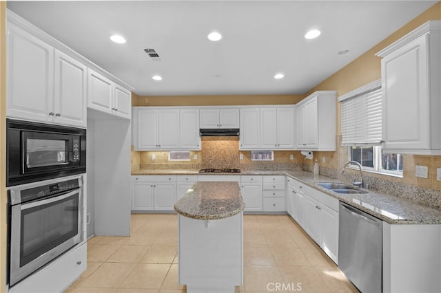 kitchen featuring a sink, stainless steel appliances, white cabinetry, a kitchen island, and decorative backsplash