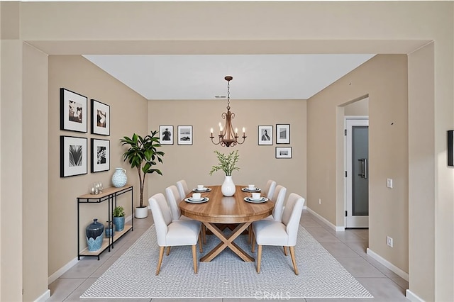 dining room featuring light tile patterned floors, a chandelier, and baseboards