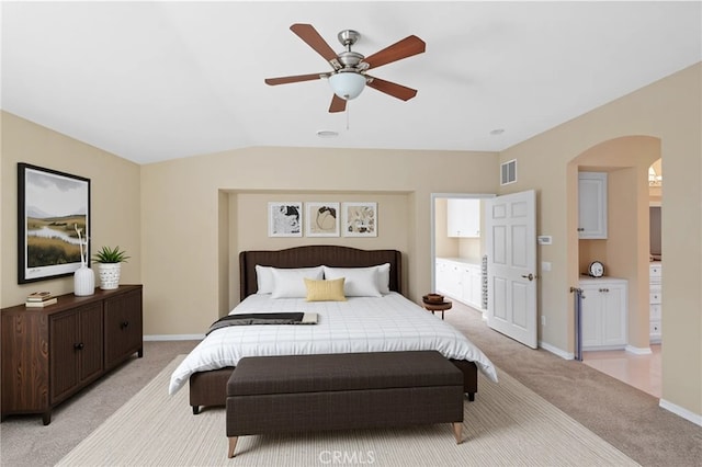bedroom featuring light colored carpet, arched walkways, baseboards, a ceiling fan, and vaulted ceiling
