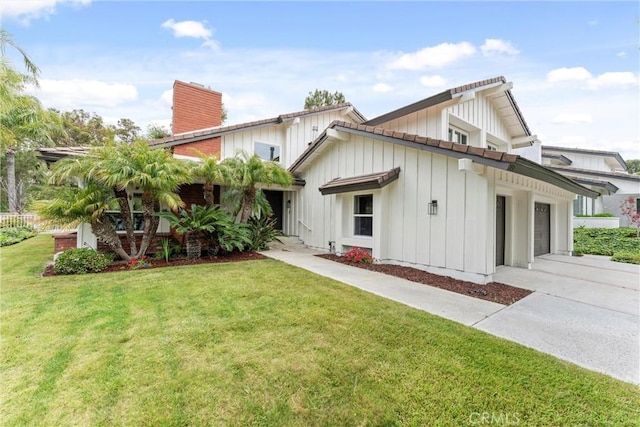 5431 Via Ontiveros, Yorba Linda, CA 92887 - rear view of house with an attached garage, driveway, a yard, a chimney, and board and batten siding