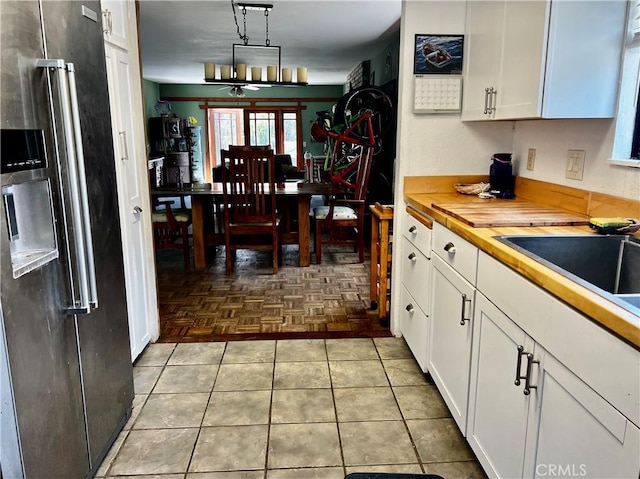 kitchen with high quality fridge, white cabinetry, and wooden counters