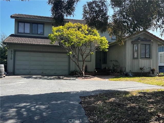 view of front of home featuring an attached garage, a tile roof, central AC unit, driveway, and entry steps