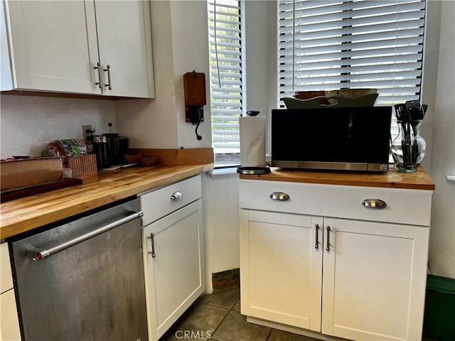 kitchen with butcher block counters, tile patterned floors, white cabinets, and dishwasher