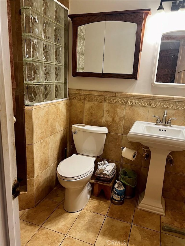 bathroom featuring a wainscoted wall, tile walls, toilet, and tile patterned floors