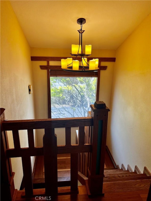 stairs with a notable chandelier and wood finished floors