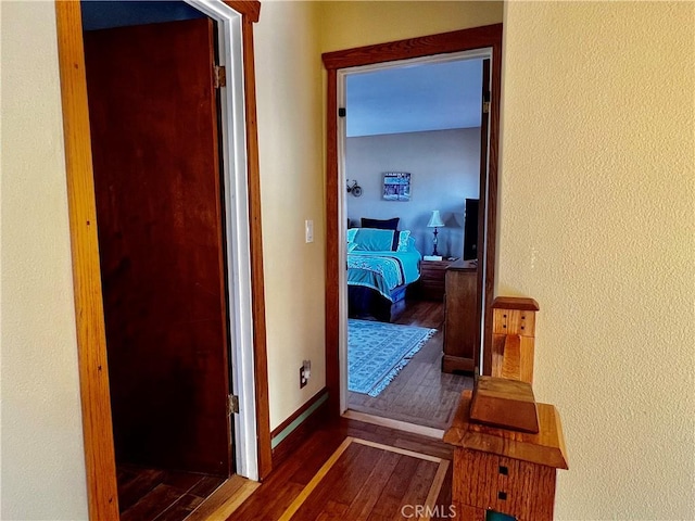corridor with baseboards and wood finished floors