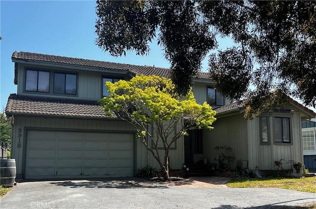 view of front facade with entry steps, an attached garage, a tiled roof, and driveway