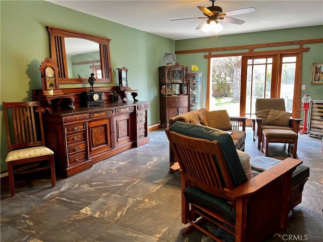 living area with ceiling fan and stone finish floor