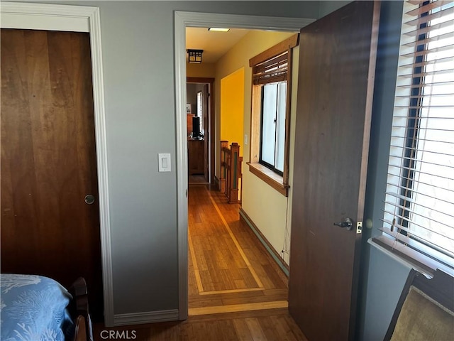 hallway featuring a wealth of natural light, wood finished floors, and baseboards