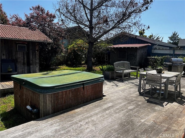 wooden terrace featuring outdoor dining area, area for grilling, a covered hot tub, and an outbuilding