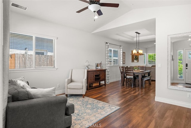 living room featuring baseboards, ceiling fan with notable chandelier, and dark wood-type flooring