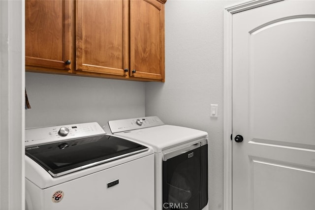 washroom with washer and clothes dryer and cabinet space