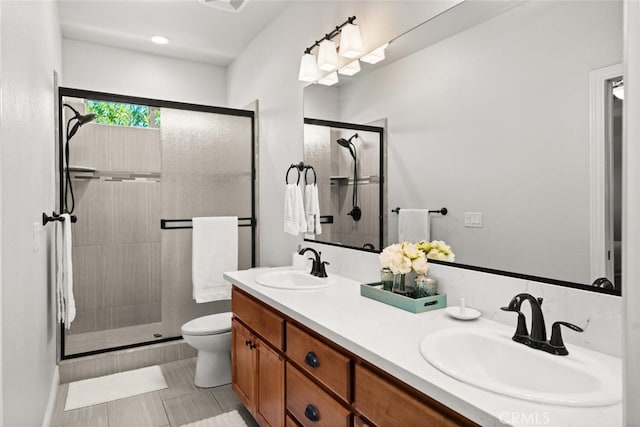 full bathroom featuring double vanity, toilet, a stall shower, and a sink