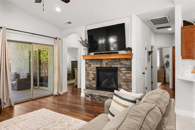 living area with a fireplace, ceiling fan, visible vents, and vaulted ceiling