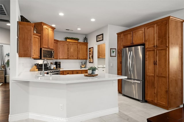 kitchen with a peninsula, light countertops, appliances with stainless steel finishes, and visible vents
