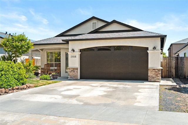 view of front of home with fence, an attached garage, stone siding, driveway, and stucco siding