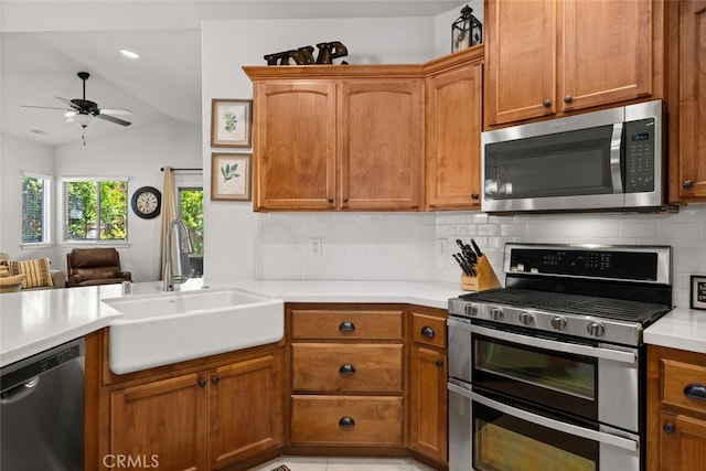 kitchen with a sink, ceiling fan, light countertops, appliances with stainless steel finishes, and tasteful backsplash