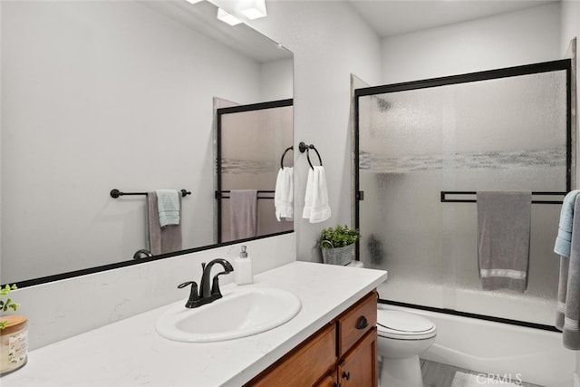 full bath with enclosed tub / shower combo, vanity, and toilet