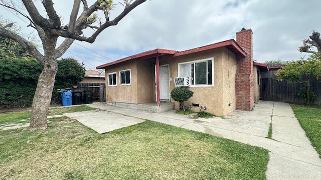 view of front of house with fence, stucco siding, a front lawn, and a chimney