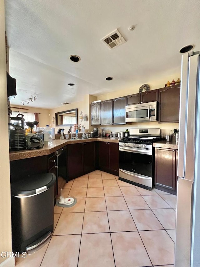 kitchen with light tile patterned floors, stainless steel appliances, visible vents, and dark brown cabinets