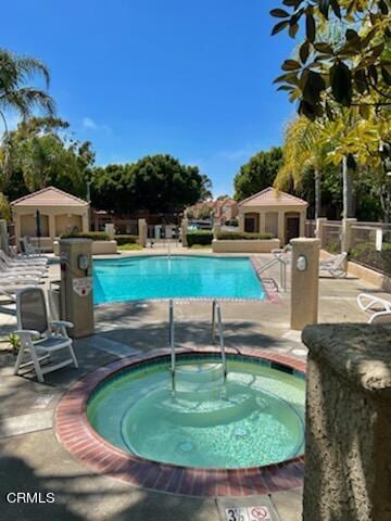 community pool with a hot tub, a patio area, and an outbuilding