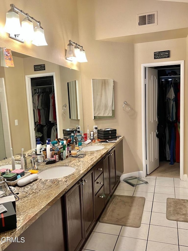 bathroom featuring a sink, visible vents, tile patterned flooring, a spacious closet, and double vanity