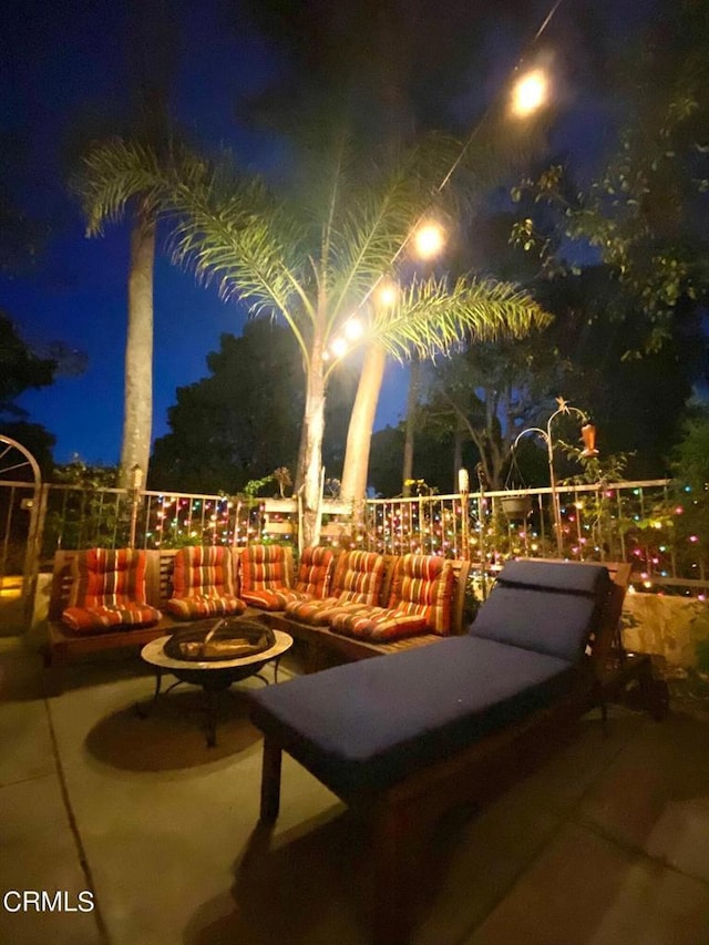 patio at night with an outdoor living space with a fire pit