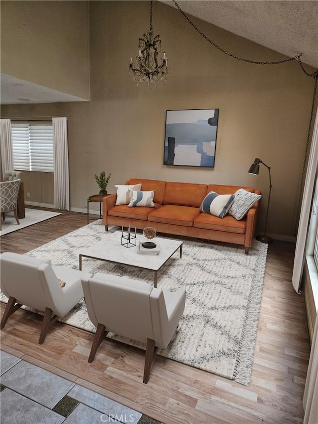 living area featuring vaulted ceiling, baseboards, a notable chandelier, and wood finished floors