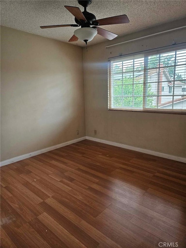 empty room featuring a textured ceiling, baseboards, a ceiling fan, and wood finished floors
