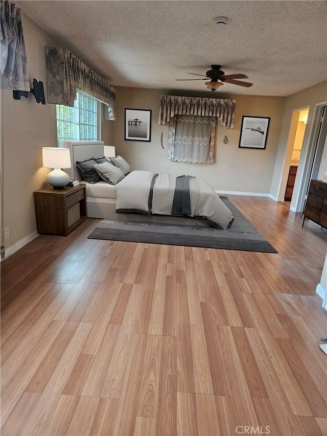 bedroom with baseboards, ceiling fan, a textured ceiling, and wood finished floors