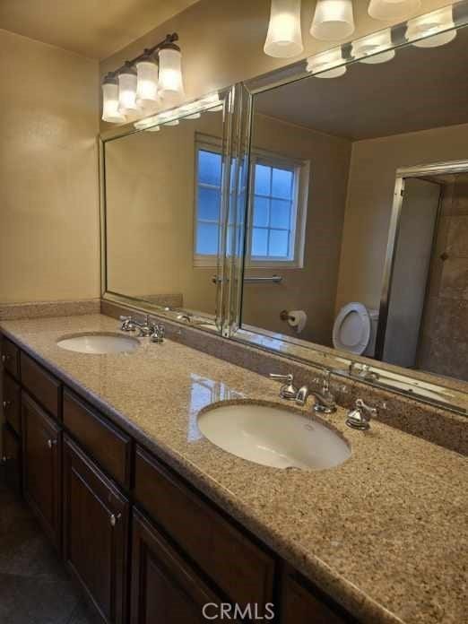 full bath with a sink, double vanity, and a shower with shower door