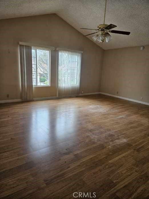 empty room with a ceiling fan, baseboards, a textured ceiling, and wood finished floors
