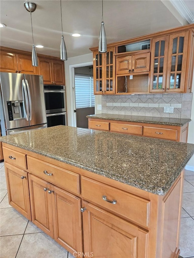 kitchen with light tile patterned floors, backsplash, dark stone countertops, and appliances with stainless steel finishes