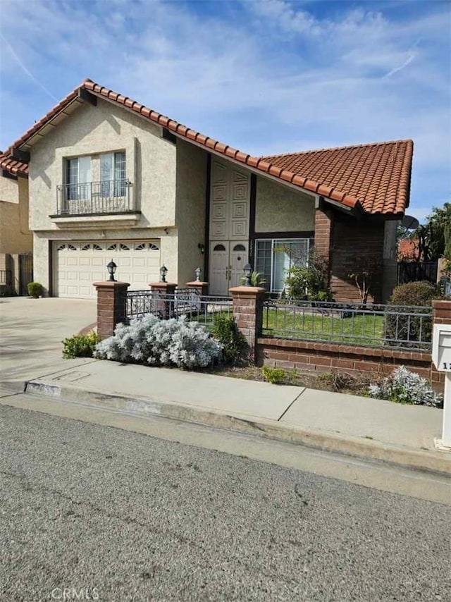 mediterranean / spanish home with driveway, a tile roof, a garage, stucco siding, and a fenced front yard