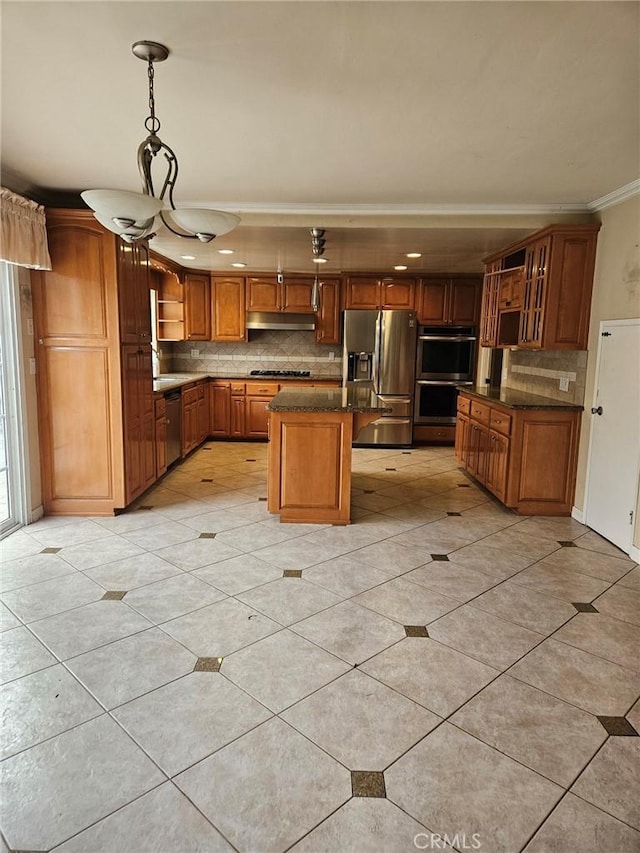 kitchen with stainless steel appliances, brown cabinets, ornamental molding, under cabinet range hood, and backsplash