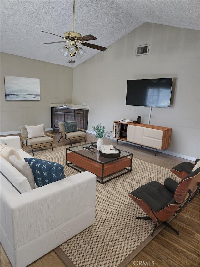 living room featuring a ceiling fan, baseboards, a textured ceiling, and wood finished floors