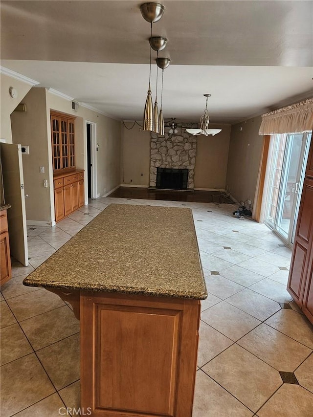 kitchen with decorative light fixtures, light tile patterned floors, open floor plan, a kitchen island, and a fireplace