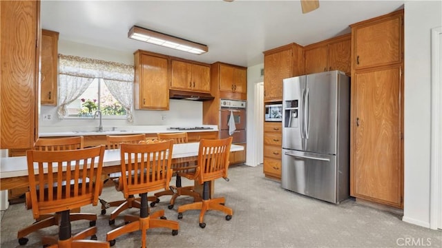 5427 Picker St, Riverside, CA 92503 - kitchen with stainless steel appliances, a sink, under cabinet range hood, brown cabinetry, and light countertops