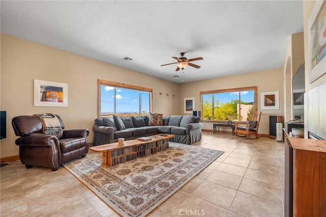 living room with light tile patterned flooring, a textured ceiling, visible vents, and a ceiling fan