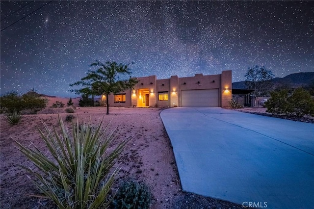 adobe home featuring stucco siding, driveway, and a garage