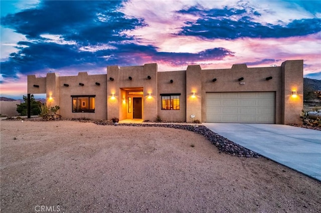 adobe home featuring concrete driveway, a garage, and stucco siding