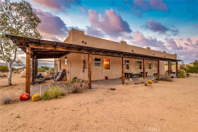 61465 Latham Trl, Joshua Tree, CA 92252 - back of property at dusk featuring a patio, a gate, and fence
