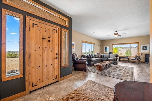living area featuring a ceiling fan, baseboards, and light tile patterned flooring