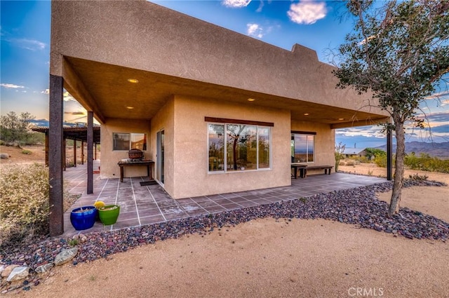 rear view of house featuring a patio area and stucco siding