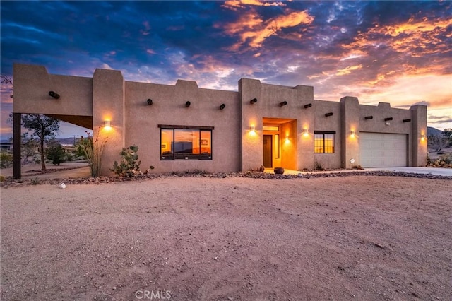 pueblo-style home with an attached garage and stucco siding