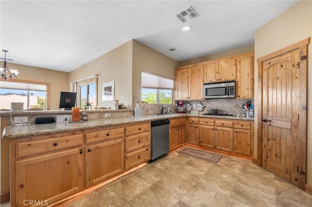 61465 Latham Trl, Joshua Tree, CA 92252 - kitchen with appliances with stainless steel finishes, a peninsula, decorative backsplash, light stone counters, and a chandelier