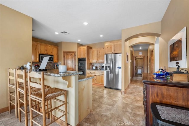 61465 Latham Trl, Joshua Tree, CA 92252 - kitchen featuring stainless steel appliances, arched walkways, a peninsula, a kitchen breakfast bar, and dark stone counters