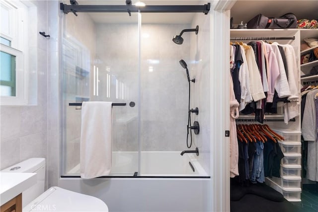 bathroom with toilet, enclosed tub / shower combo, and a spacious closet