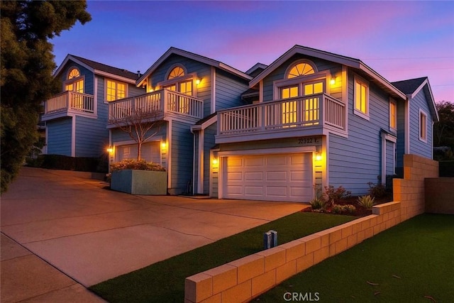 view of front facade with driveway, an attached garage, and a balcony