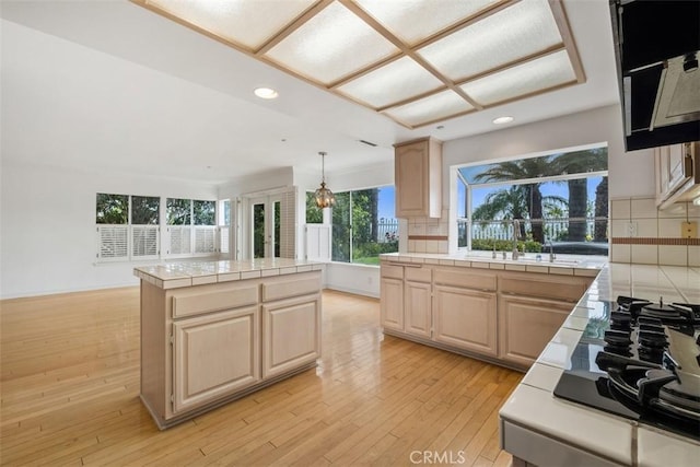 kitchen featuring tile countertops, recessed lighting, light brown cabinetry, light wood finished floors, and a kitchen island